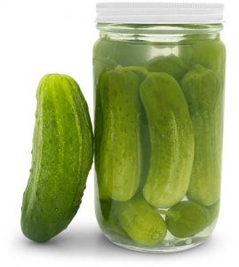 Jar of pickles with one outside leaning against jar