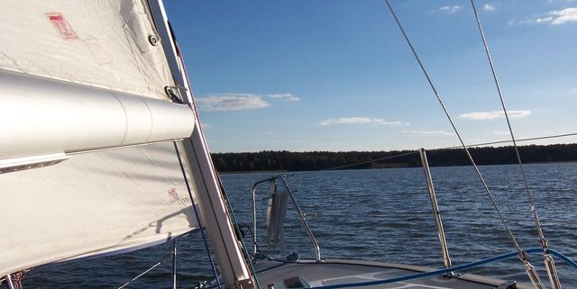 front of small sailboat heading towards land in distance